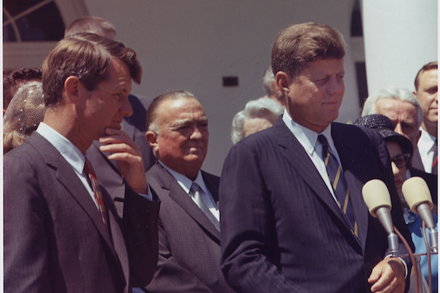 Two men in suits in foreground with other people behind