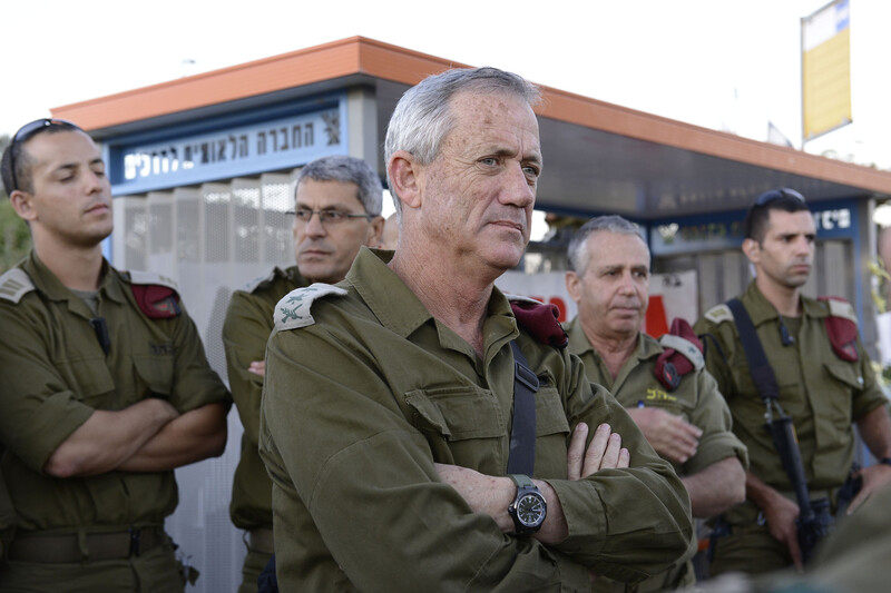 Several men in military uniforms stand with arms folded