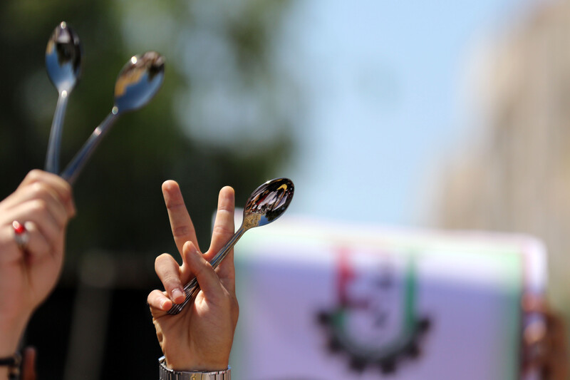 Hands hold up spoons and victory signs 