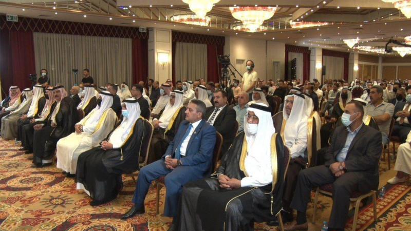 An audience of dozens seated in a conference room 