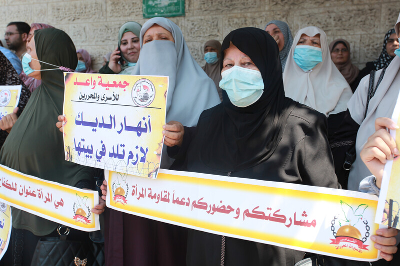 Women stand close together holding signs