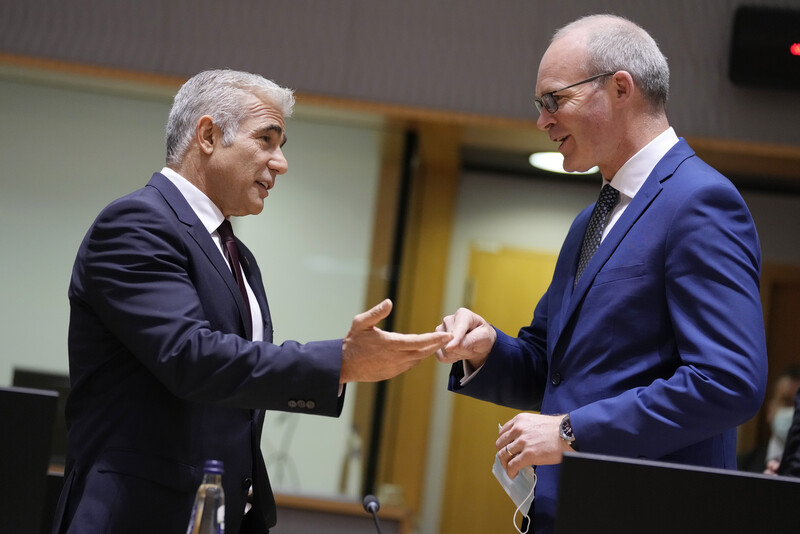 Two men in suits smile and gesture