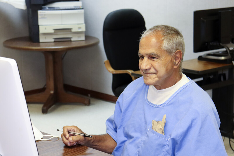 Smiling man sits in front of computer screen