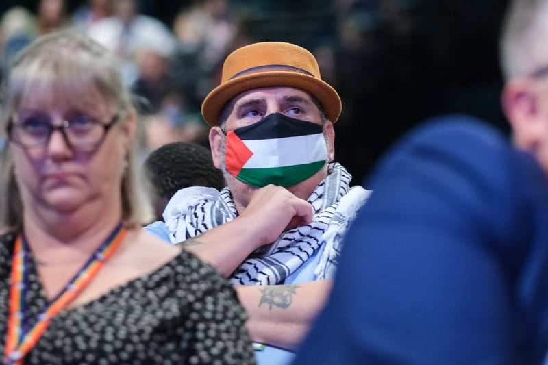 Man in hat wears Palestinian headscarf and facemask in colors of Palestinian flag