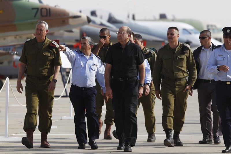 A group of men in uniforms walk in front of warplanes