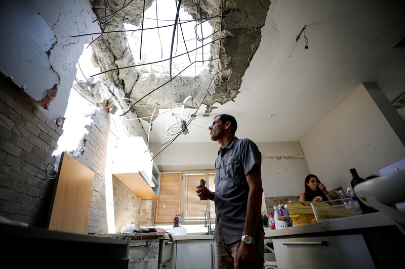 Man stands underneath hole in kitchen ceiling