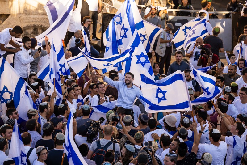 Man in crowd waving Israeli flags