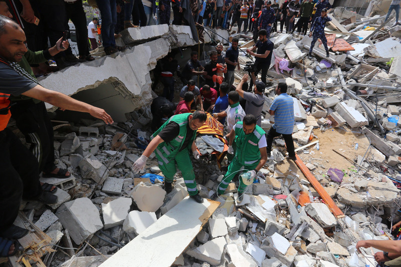 Rescue workers surrounded by rubble carry a stretcher