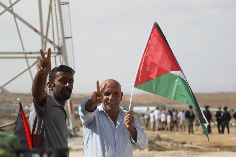 Two men with Palestinian flag make victory sign
