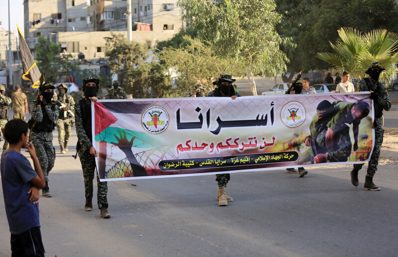 Men dressed in military uniform hold banner 