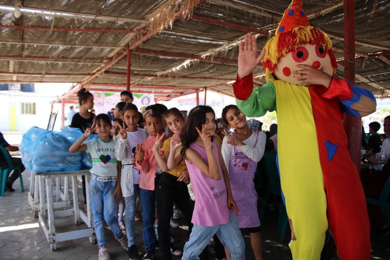 Children play behind a clown