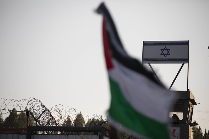 A Palestinian flag flutters in front of an Israeli flag