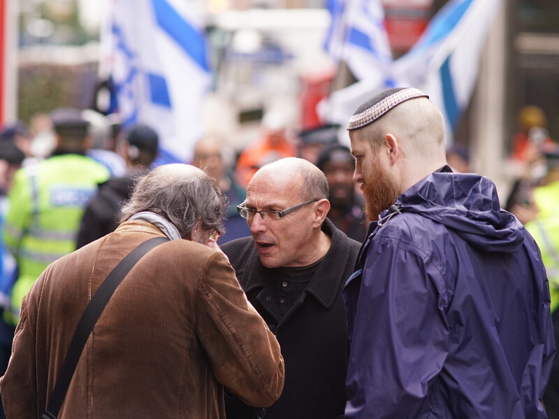 Three men at a demonstration with Israeli flags