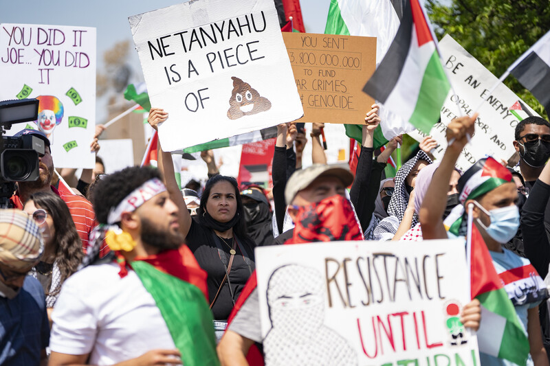 Protesters hold up posters and banners against Israeli air strikes in Gaza