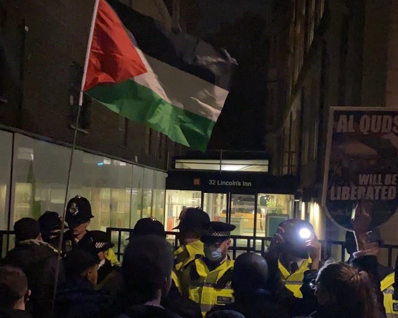 Protesters with a Palestinian flag facing police