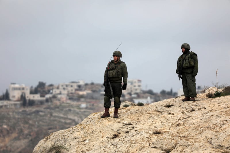 Men in combat gear stand on hilltop