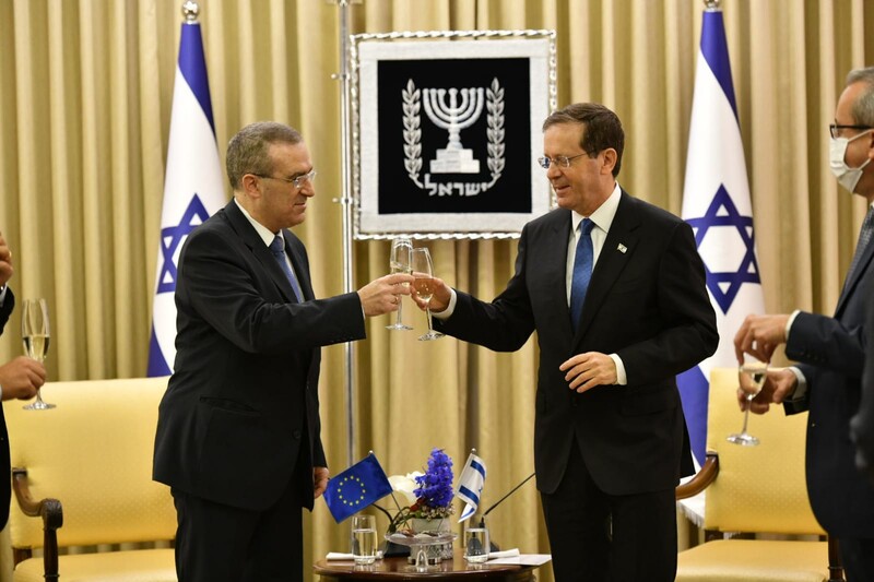 Two men raise champagne glasses in front of Israeli flags