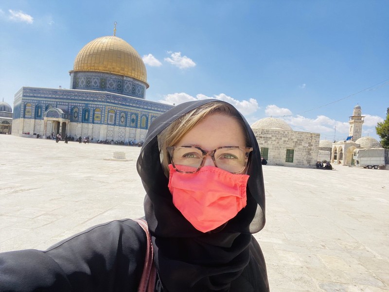 Woman in face mask stands in front of Jerusalem's Dome of the Rock