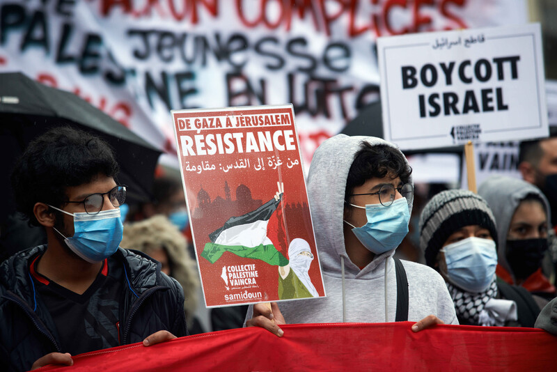 Two men wear masks while holding signs