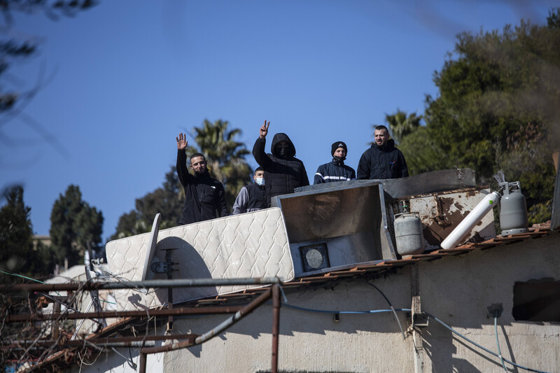 Four men stand on top of a roof 