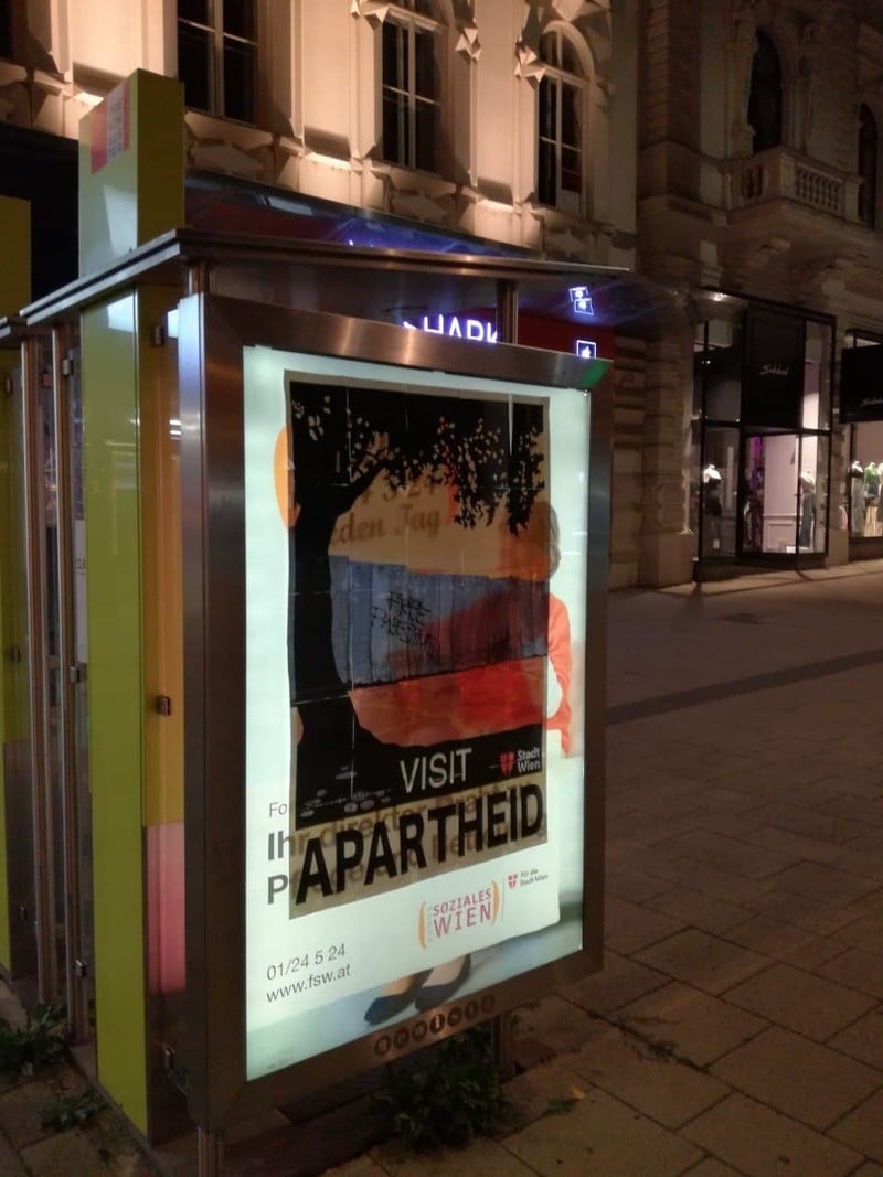 A poster pasted on a lighted panel in a darkened city street
