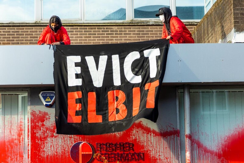 Two activists on a rooftop with a sign