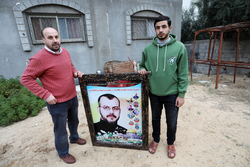 Two men hold poster showing photos of now deceased relatives