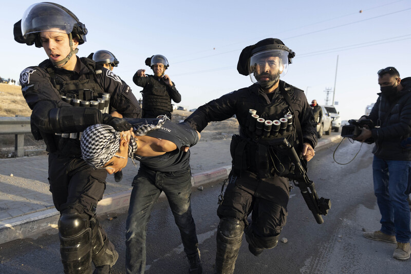 Two heavily armed Israeli police arrest a young boy