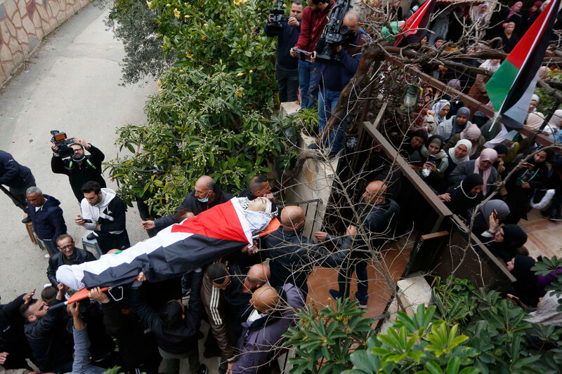 Mourners carry the body of a boy wrapped in a flag on a stretcher 