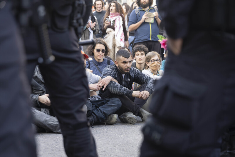 A group of activists sit on the ground surrounded by police 