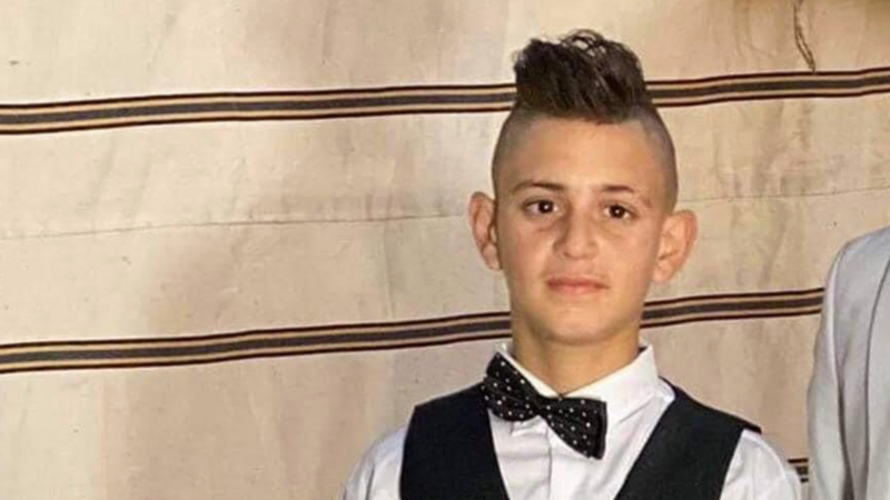 A boy wearing a tuxedo is smiling