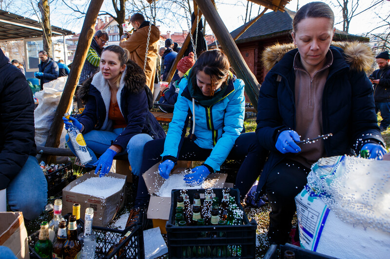 People in a park work over crates full over bottles