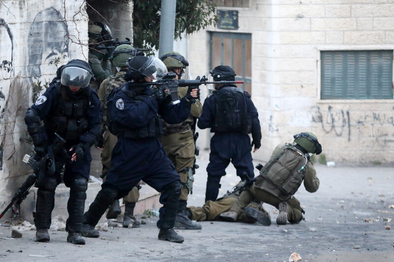 Heavily armed forces take position at a street corner 