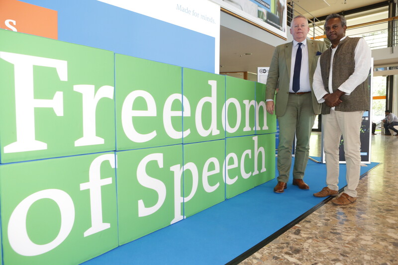 Two people stand next to large sign