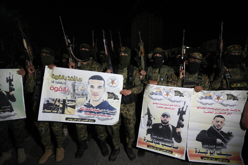 Armed militants hold up their weapons along with posters