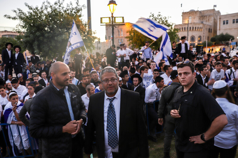 Three men stand in the front while others wave flags behind them