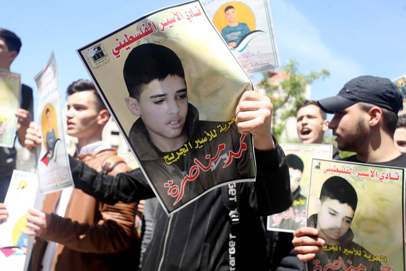 Protestors hold up a poster of a young boy calling for his release from Israeli prison