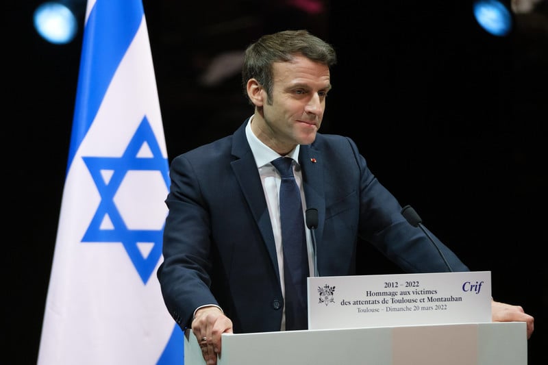 Macron stands at podium beside flag of Israel