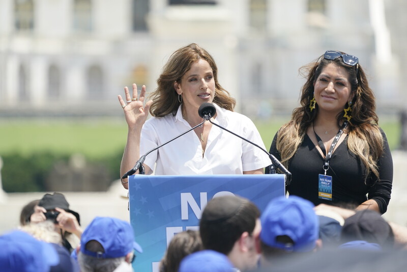 Two women stand before crowd