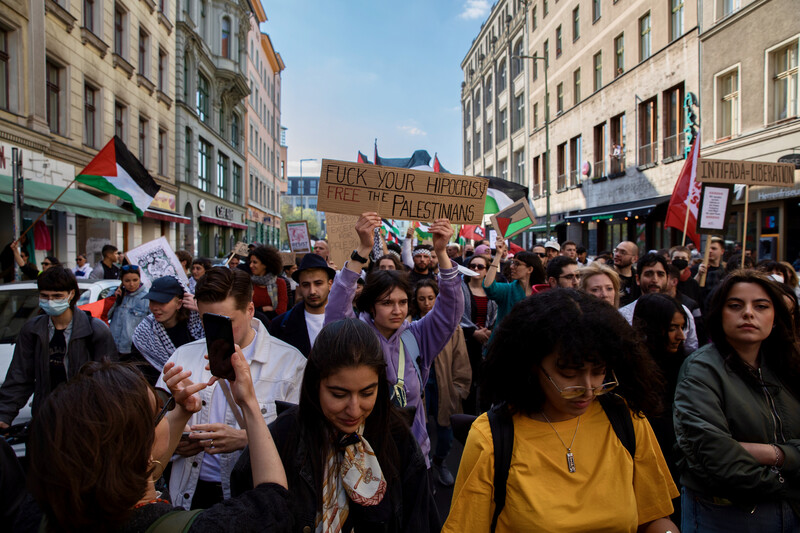 Large crowd walks down street with signs and flags