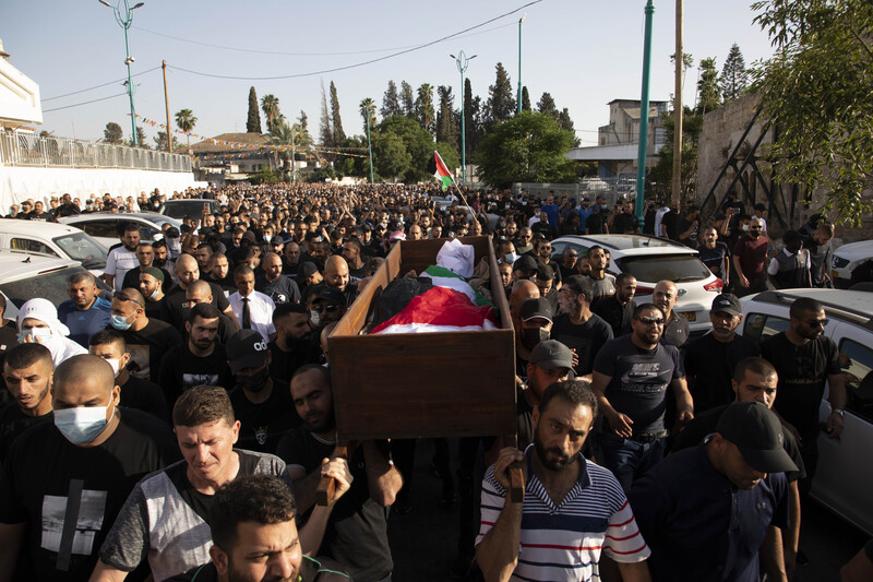 People carry a body wrapped in a flag in a coffin 