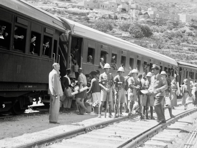 Carriages with people inside and outside and a row of soldiers in helmets