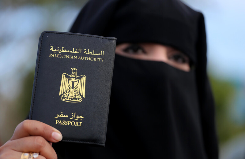 A woman holds up her Palestinian travel document