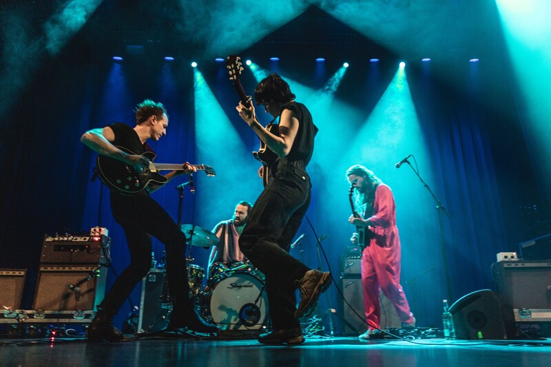 Band performs on stage with colorful lights 