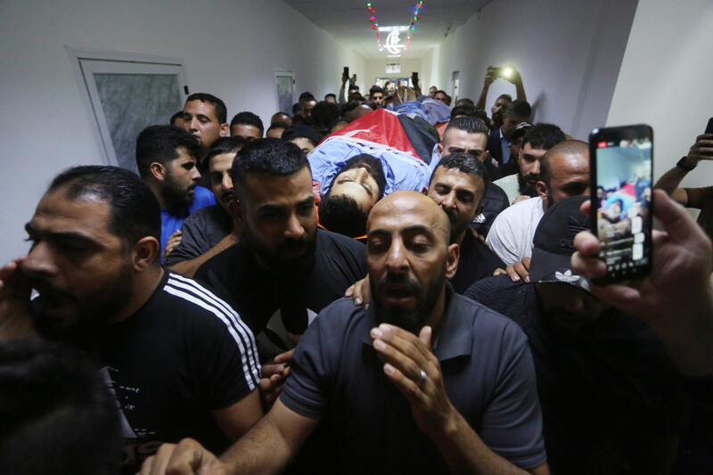 Men carry a flag-wrapped body on a stretcher 