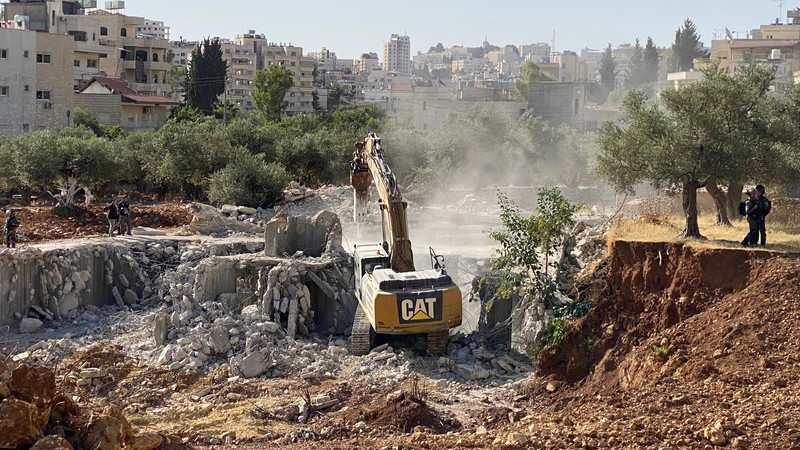 An Israeli bulldozer razes a Palestinian building under construction in the West Bank city of Bethlehem on 9 June. Wissam Zarina, son of the owner of the house, told WAFA news agency that a large force of the Israeli army stormed the Bir Aouneh area of Beit Jala and demolished their one-story house on the pretext that it was being built without a permit.  (Ahmad Tayem/ APA images)
