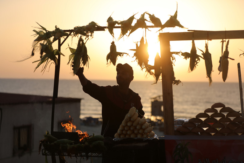 A vendor sells grilled corn on the Gaza City coast on 9 June.  (Atia Darwish/ APA images)