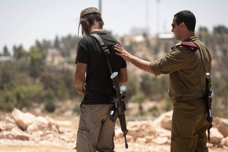 Israeli army commander Yehuda Rozilio escorts armed Jewish settlers during a demonstration held by Palestinians in Masafer Yatta in the southern West Bank following an Israeli high court ruling paving the way for the forced transfer of eight Palestinian communities in the area, 10 June.  (Oren Ziv/ ActiveStills)