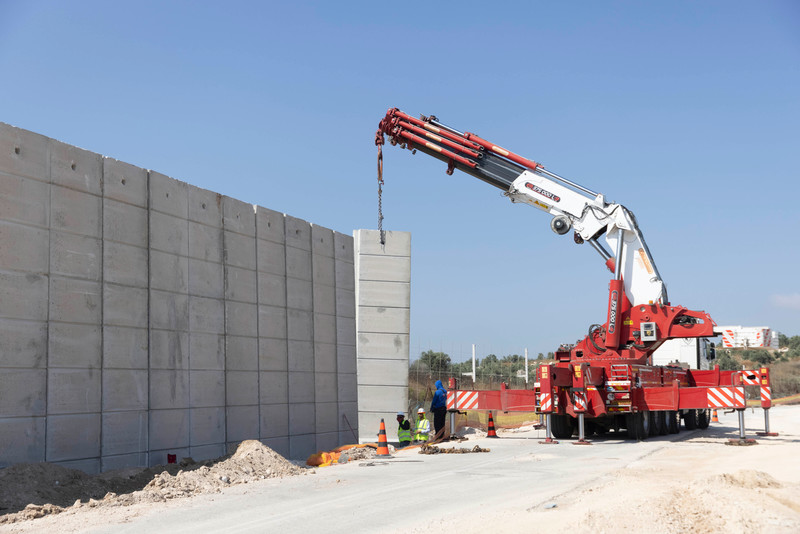 Workers place a concrete slab during the erection of a new barrier parallel to the Israel’s West Bank wall near the village of Salem on 23 June. The concrete wall will be nearly 30 miles in length in order to block holes in the barrier that Palestinians from the West Bank use to enter Israel.  (Oren Ziv/ ActiveStills)