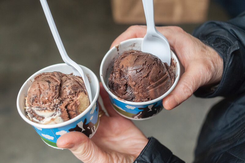 A person holds two cups of ice cream